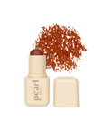 Pearl Beauty cream blush stick in a warm terracotta orange shade, shown with its beige cap off and a textured smear of the powder above, on a white background.