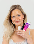 Woman holding skincare products against a plain background