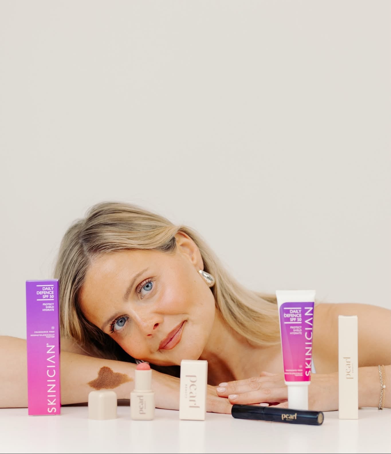 Woman lying on a white surface with skincare products around her