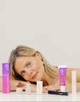 Woman lying on a white surface with skincare products around her