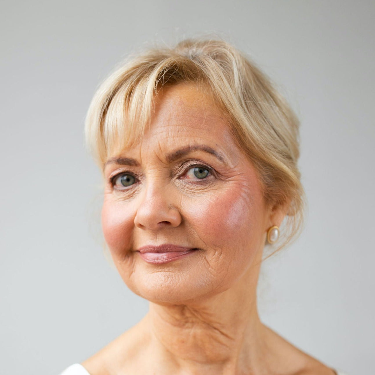 Close-up of mature model wearing Pearl Beauty Core Four Put Together cream blush stick medium rose colour cream blush vegan cruelty-free